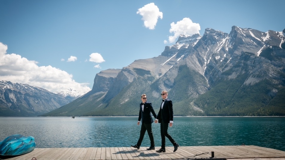 Couple in suits walking along dock at Lake Minnewanka
