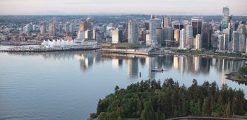 Aerial photo of the Vancouver city skyline with Stanley Park in the foreground.
