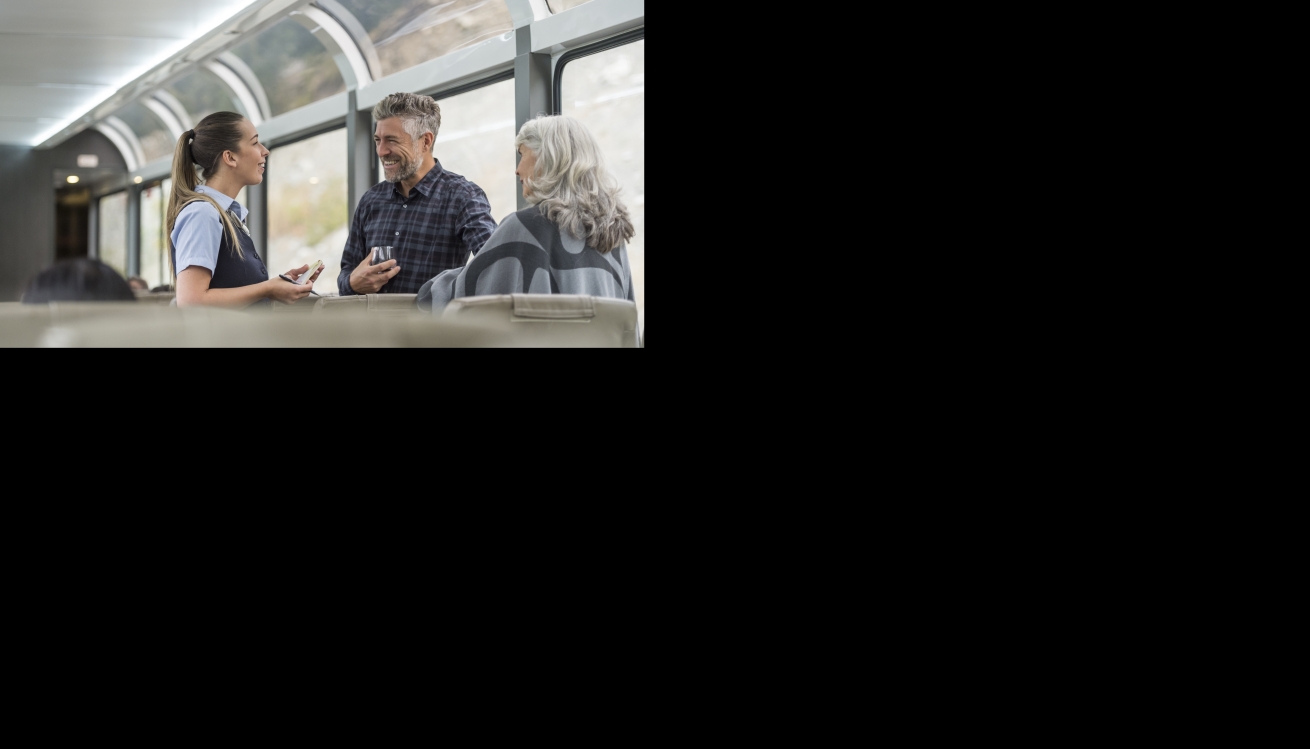 Rocky Mountaineer Host helping guests on the train.