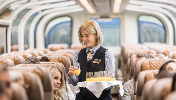 rocky moutaineer host hands out mimosas onboard the train in goldleaf service