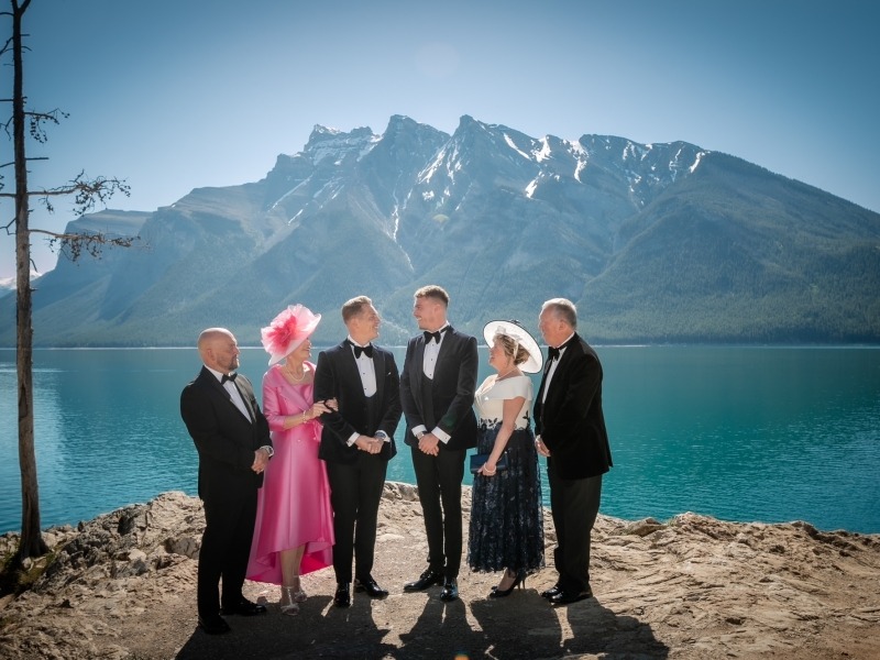 Family in wedding attire standing in front of Lake Minnewanka